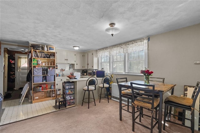 dining area featuring a textured ceiling and light colored carpet