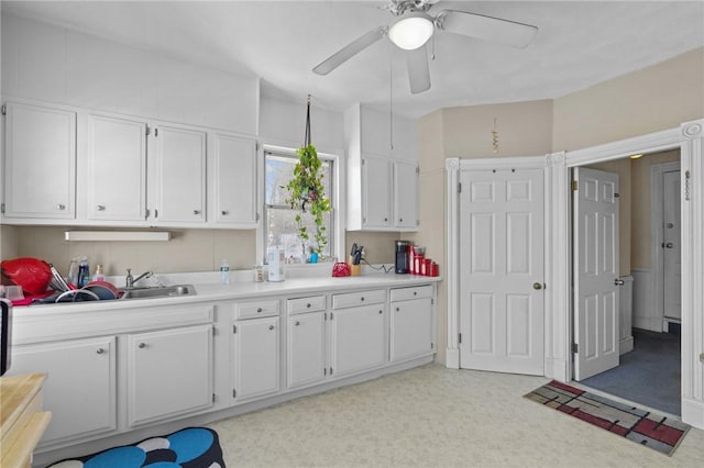 kitchen with light countertops, a sink, a ceiling fan, and white cabinets