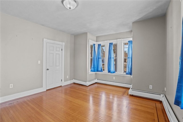 unfurnished room featuring light wood-type flooring, a baseboard radiator, and baseboards