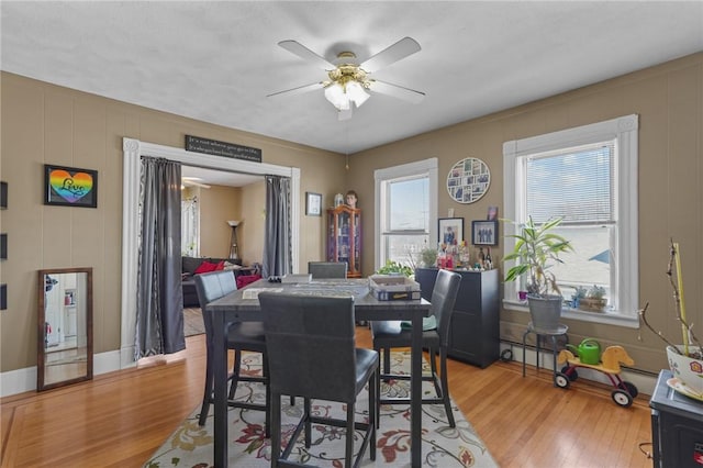 dining space featuring baseboards, ceiling fan, and light wood finished floors