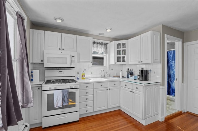 kitchen featuring glass insert cabinets, white appliances, light countertops, and white cabinets