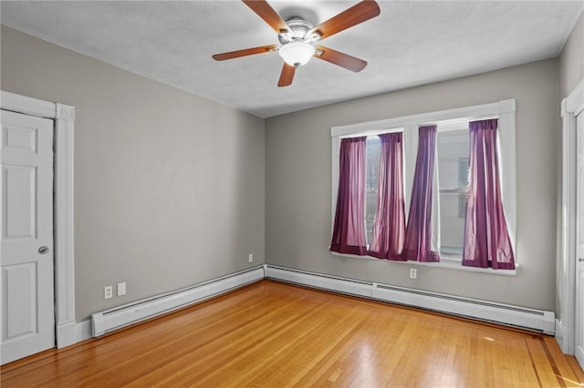 unfurnished room featuring baseboard heating, wood finished floors, and a ceiling fan