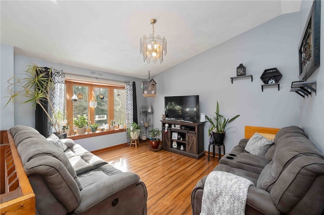 living room with baseboards, vaulted ceiling, light wood finished floors, and an inviting chandelier