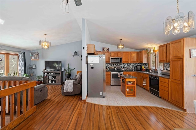 kitchen with dark countertops, open floor plan, an inviting chandelier, stainless steel appliances, and open shelves