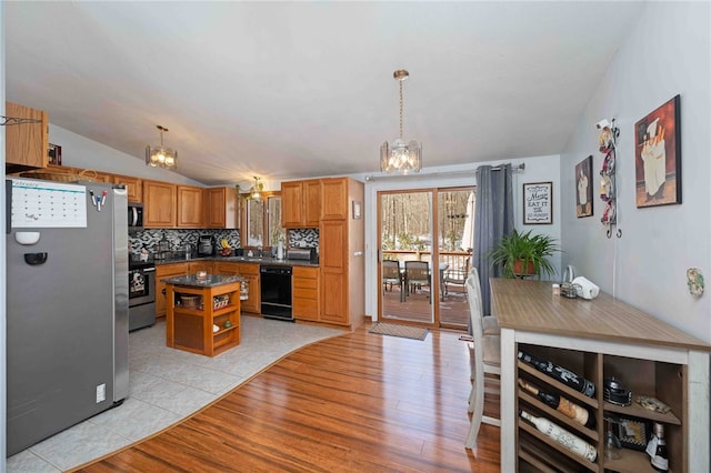 kitchen featuring decorative light fixtures, stainless steel appliances, dark countertops, an inviting chandelier, and a kitchen island