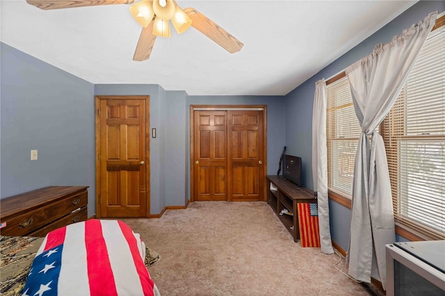 bedroom with a closet, light colored carpet, ceiling fan, and baseboards