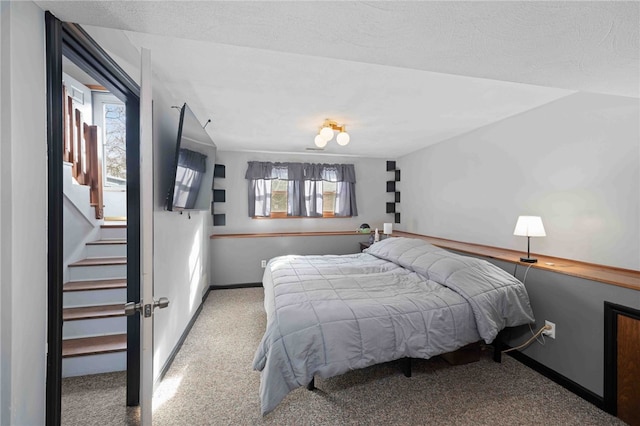 bedroom with baseboards, a textured ceiling, and light colored carpet