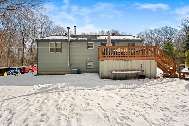 snow covered house featuring stairs and a wooden deck