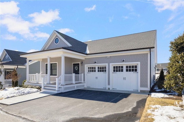 view of front of home with an attached garage, a porch, and aphalt driveway