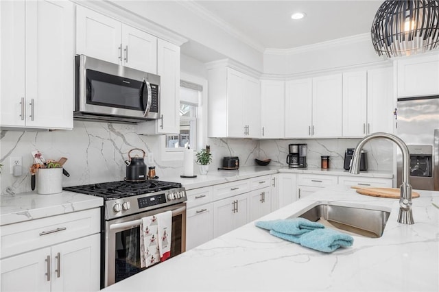 kitchen with appliances with stainless steel finishes, decorative light fixtures, crown molding, white cabinetry, and a sink