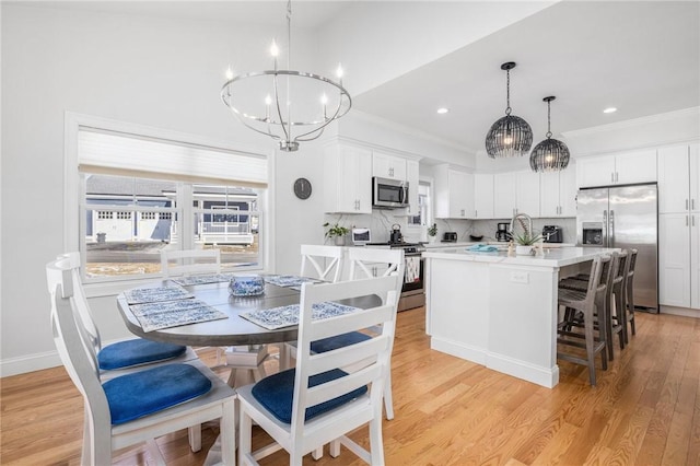 kitchen with white cabinets, light countertops, appliances with stainless steel finishes, a center island with sink, and pendant lighting