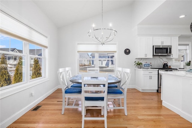 dining area with light wood-type flooring, visible vents, vaulted ceiling, and a notable chandelier