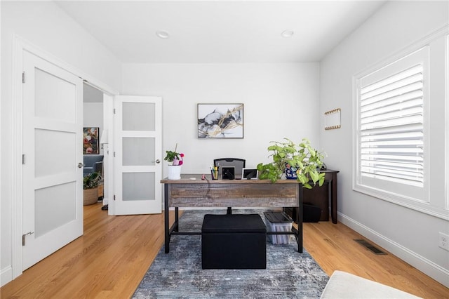 office area with wood finished floors, visible vents, and baseboards