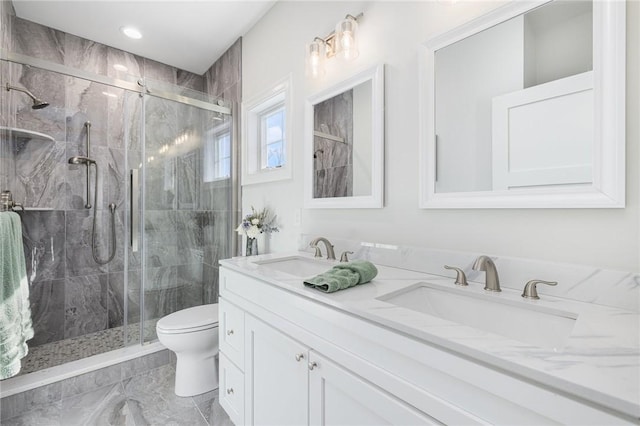 bathroom featuring a stall shower, a sink, toilet, and double vanity