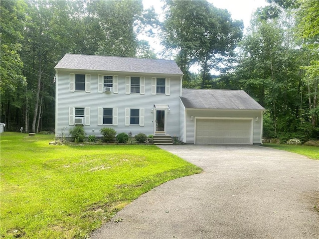 colonial-style house with aphalt driveway, an attached garage, a shingled roof, and a front yard