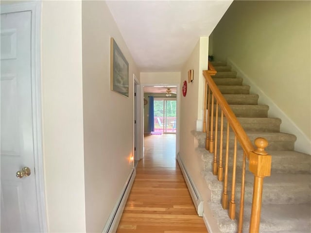 corridor featuring stairway, light wood-style flooring, and a baseboard heating unit