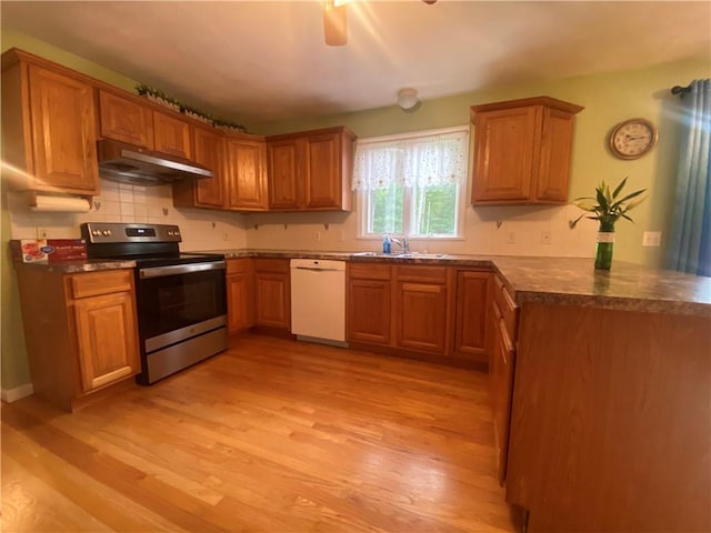 kitchen featuring dark countertops, stainless steel range with electric cooktop, a sink, dishwasher, and under cabinet range hood