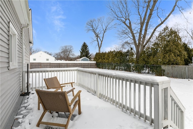 snow covered deck with a fenced backyard