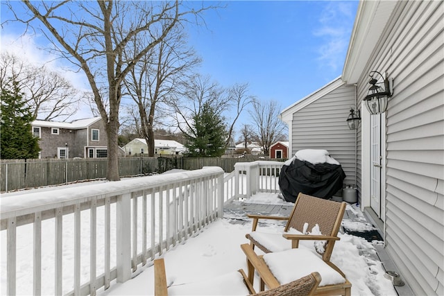 snow covered deck featuring a fenced backyard and a grill