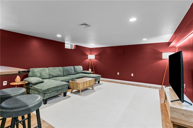 living room featuring an accent wall, light wood finished floors, visible vents, and recessed lighting