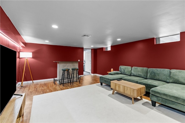 living area featuring recessed lighting, an accent wall, wood finished floors, visible vents, and a bar