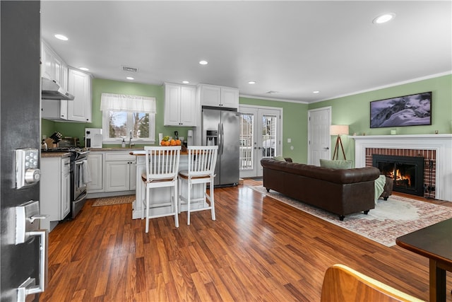 kitchen featuring stainless steel appliances, white cabinets, open floor plan, french doors, and a kitchen bar