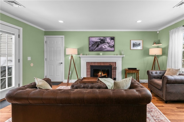 living room featuring ornamental molding, visible vents, a fireplace, and light wood-style flooring