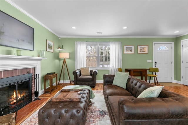 living room with light wood finished floors, a fireplace, baseboards, and crown molding