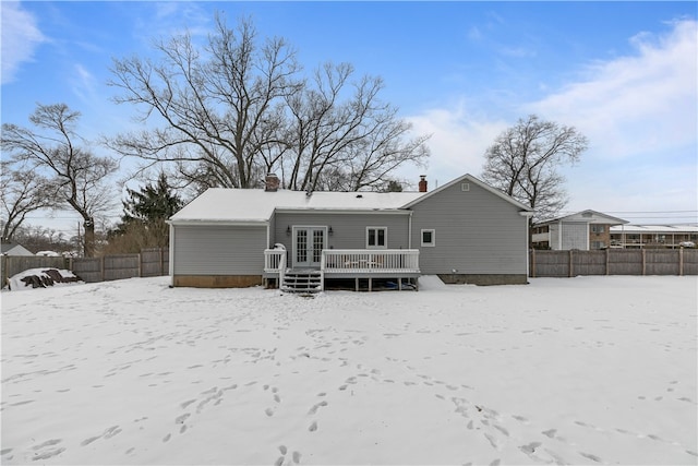 snow covered rear of property featuring fence and a deck