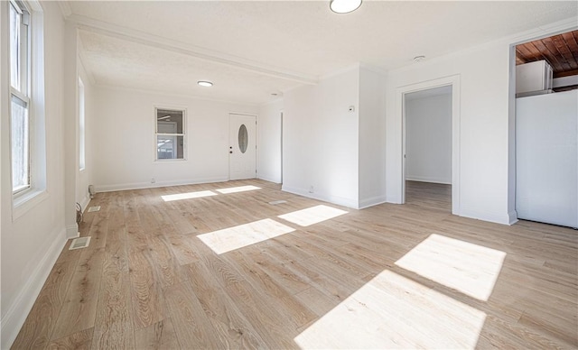 unfurnished room with light wood-type flooring, baseboards, visible vents, and ornamental molding