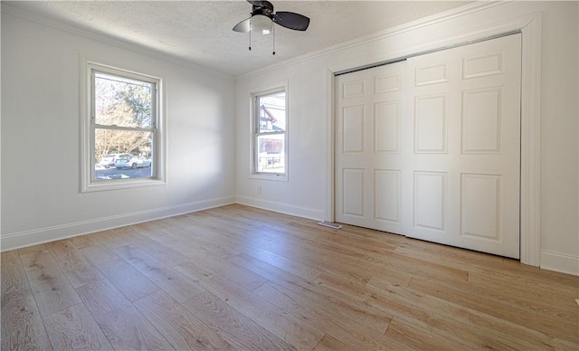 unfurnished bedroom featuring light wood-type flooring, crown molding, baseboards, and a textured ceiling