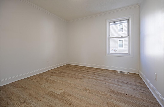 spare room with baseboards, visible vents, crown molding, and light wood finished floors