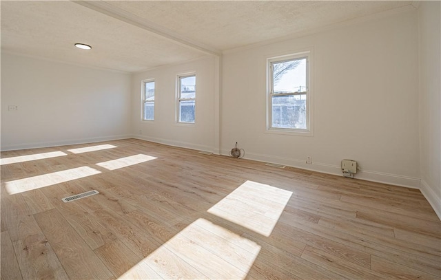 unfurnished room featuring plenty of natural light, light wood-type flooring, visible vents, and baseboards