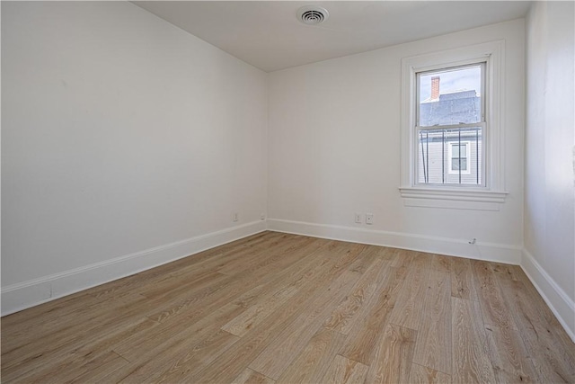 empty room featuring light wood-type flooring, visible vents, and baseboards