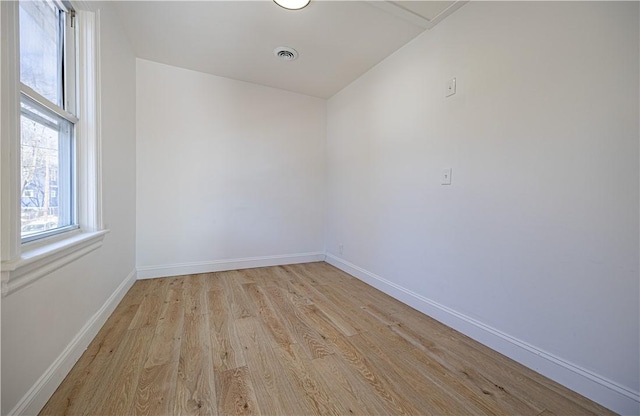 unfurnished room with light wood-type flooring, visible vents, and baseboards