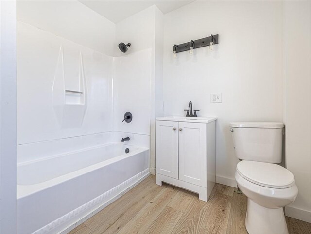 full bath with toilet, shower / bath combination, wood finished floors, vanity, and baseboards