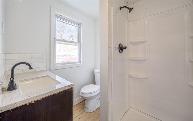 full bath featuring toilet, a stall shower, tasteful backsplash, and vanity