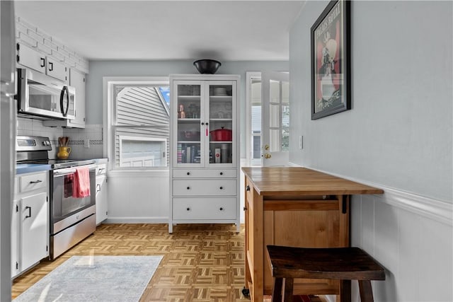 kitchen with stainless steel appliances, a wealth of natural light, and white cabinets