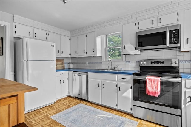 kitchen with a sink, white cabinets, appliances with stainless steel finishes, tasteful backsplash, and dark countertops