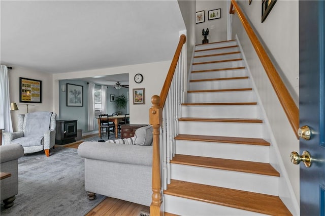 stairway with a wood stove and wood finished floors