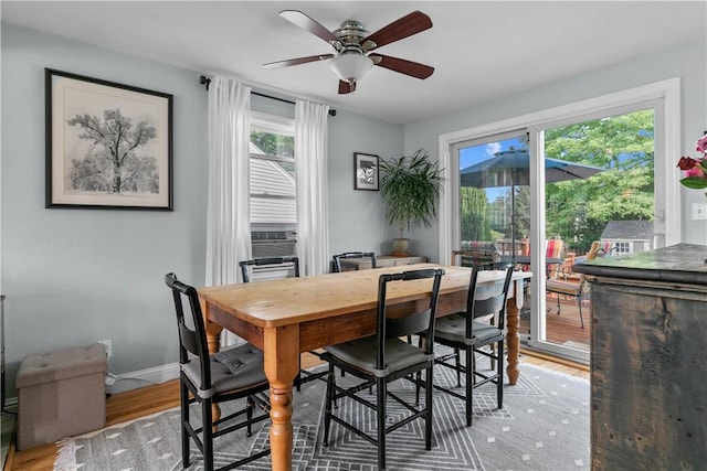 dining area featuring a ceiling fan, light wood-type flooring, cooling unit, and baseboards