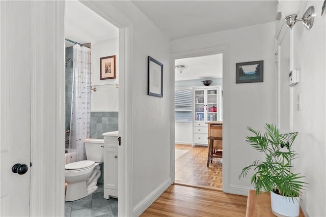 full bathroom featuring toilet, wood finished floors, vanity, baseboards, and shower / bath combo with shower curtain