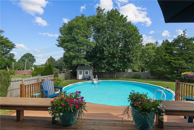 view of swimming pool featuring a fenced in pool, a fenced backyard, an outbuilding, a deck, and a shed