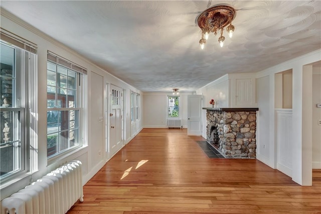 interior space with radiator heating unit, light wood-type flooring, a fireplace, and a decorative wall