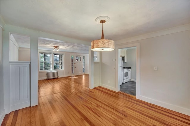 unfurnished dining area with baseboards, light wood-style flooring, and radiator heating unit