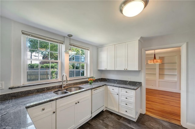 kitchen with decorative light fixtures, white cabinets, a sink, dark stone countertops, and dishwasher