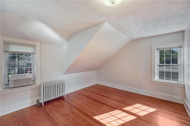 bonus room with vaulted ceiling, radiator heating unit, wood finished floors, and baseboards