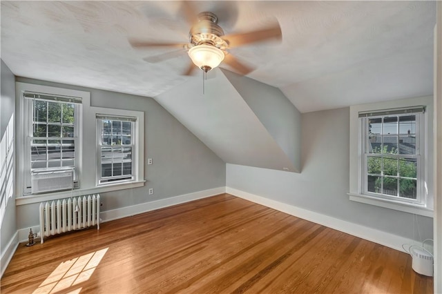 additional living space featuring vaulted ceiling, light wood finished floors, radiator heating unit, and baseboards