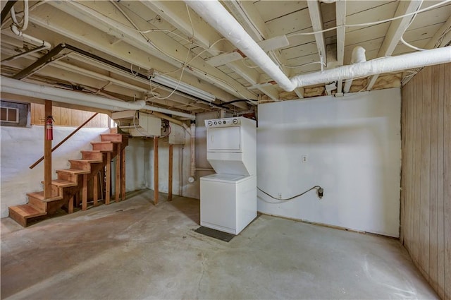 unfinished basement with stacked washer and dryer and stairway