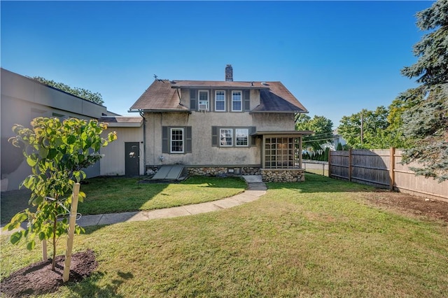 rear view of property featuring fence private yard, a chimney, a lawn, and stucco siding